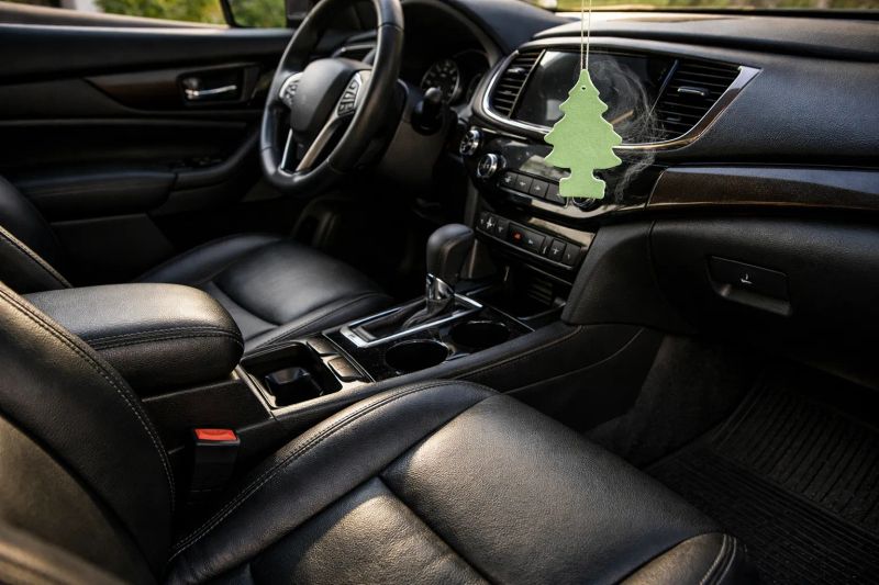 Interior of a car featuring leather seats and an air freshener.